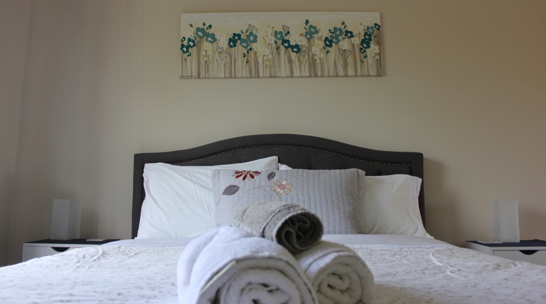 Queen bed made with white linen in the self-contained unit