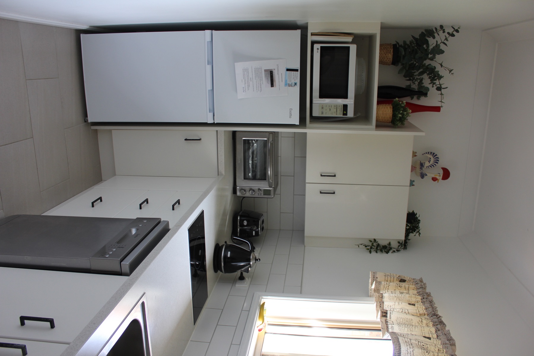 Self-catering kitchenette with white cabinets, induction cooktop and fridge