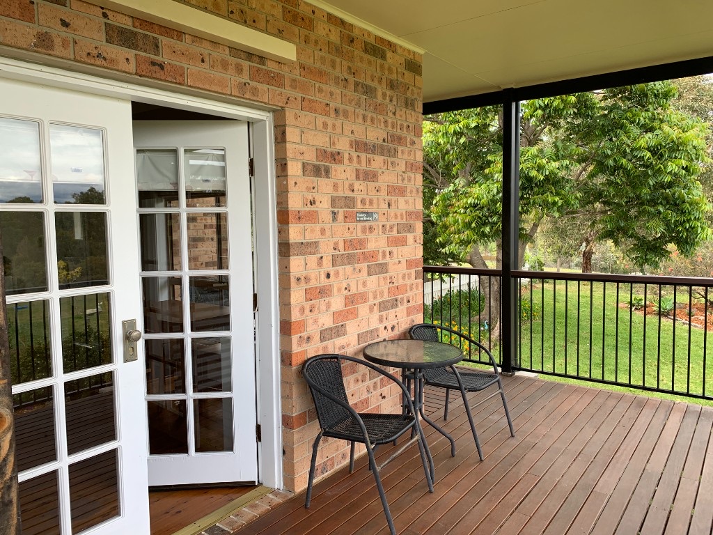 Open French doors onto the wooden verandah, with a small table looking over the lawn