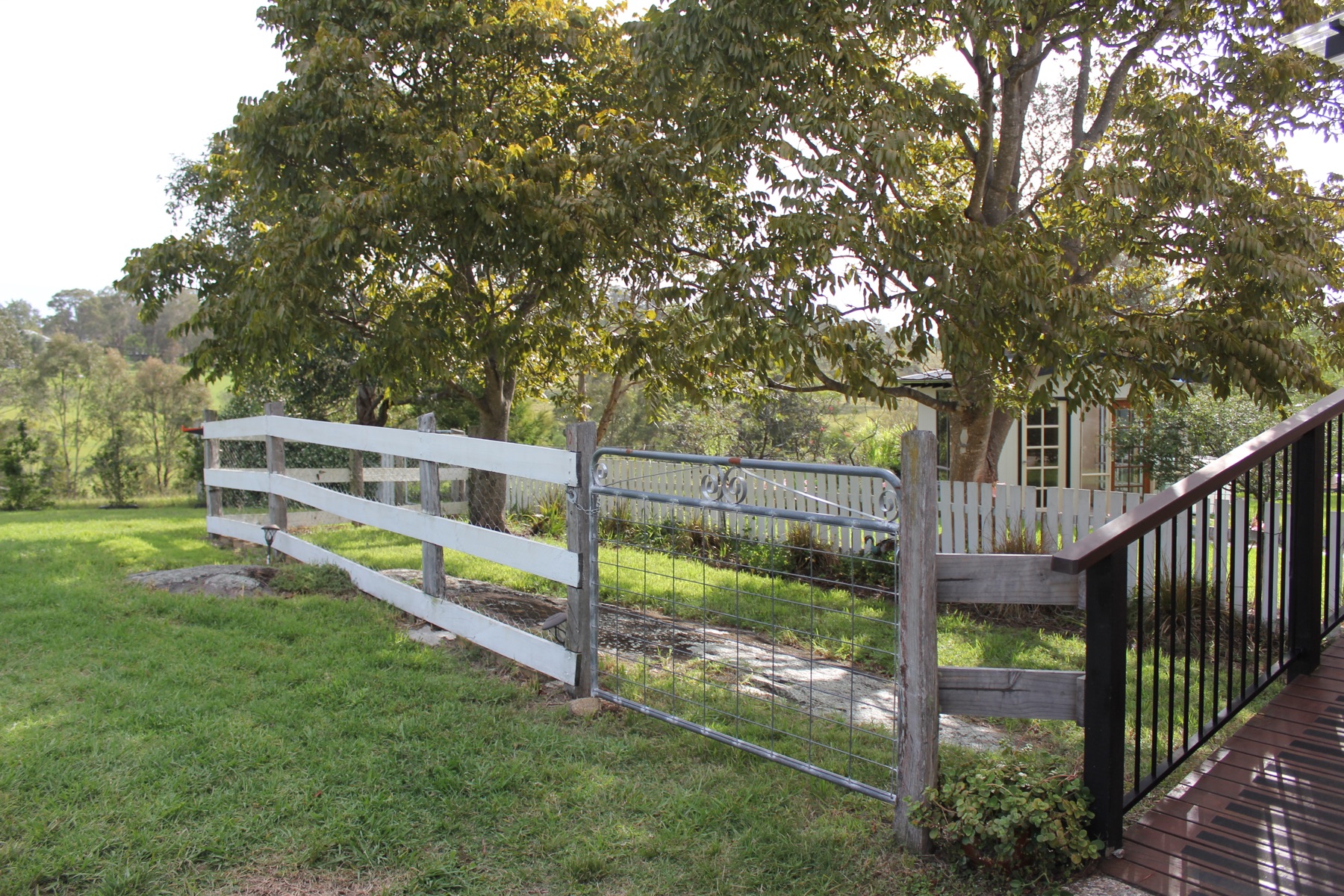 View from the deck across lawn, fence and trees to rolling hills